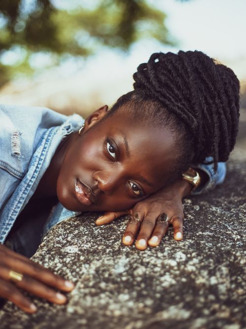 Free Portrait of a woman resting on a stone outdoors, showcasing beauty and calmness. Stock Photo