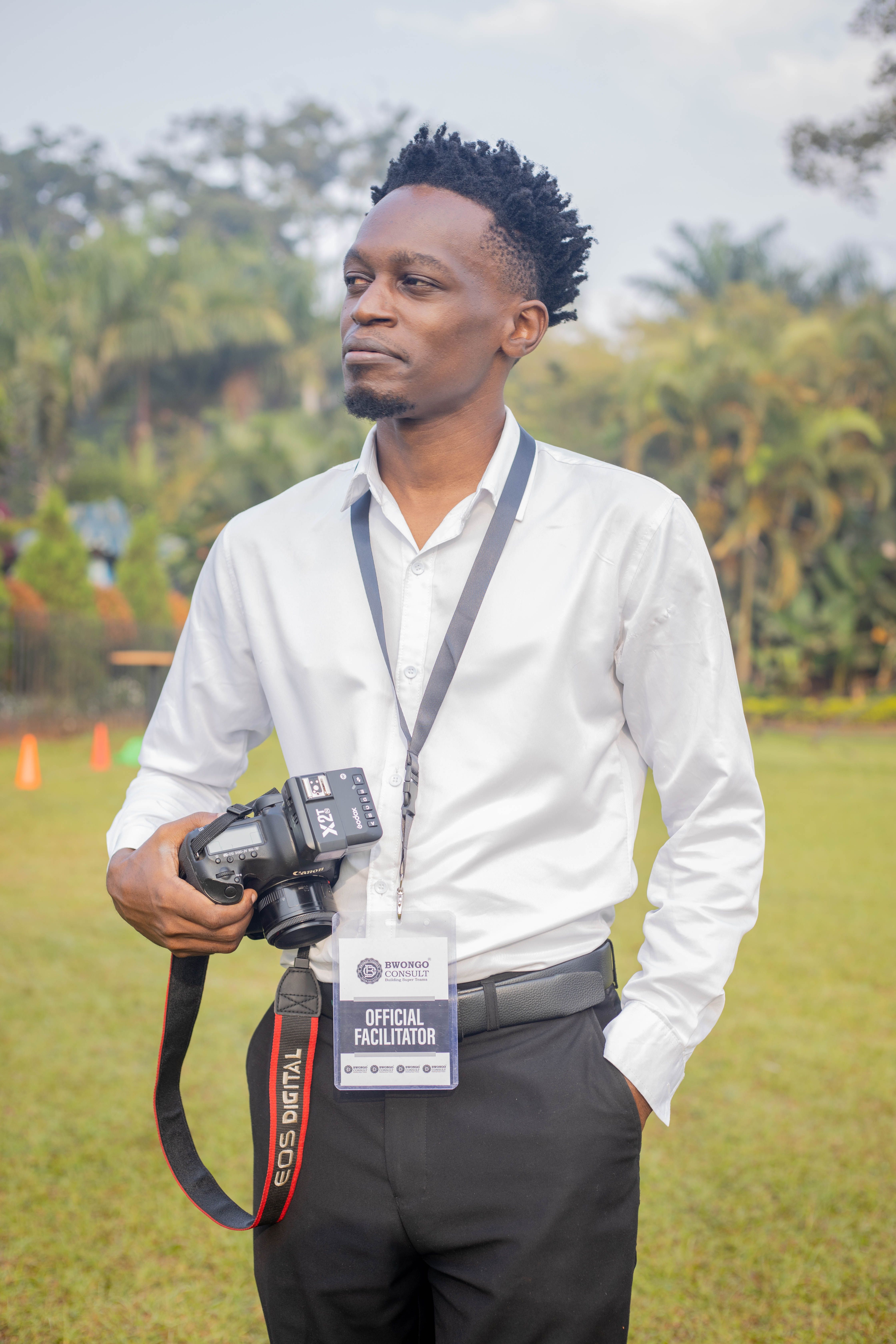 Young adult male photographer at outdoor event holding a DSLR camera.