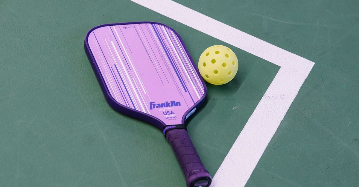 close-up of pickleball paddle and ball on court