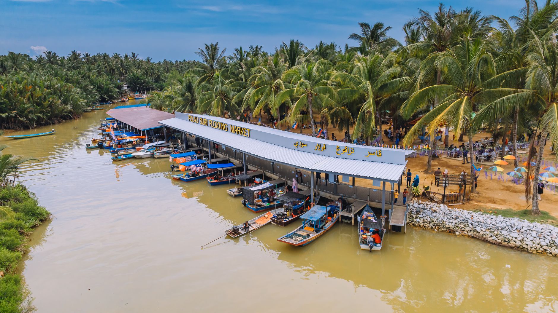 Explore the vibrant Pulau Suri Floating Market set against lush palm trees in a tropical setting.