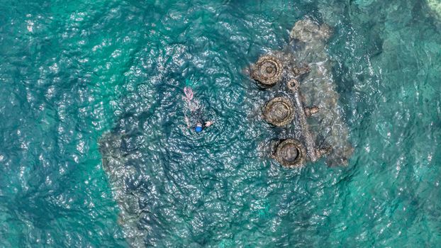 Snorkeler explores mysterious underwater shipwreck in clear turquoise waters.