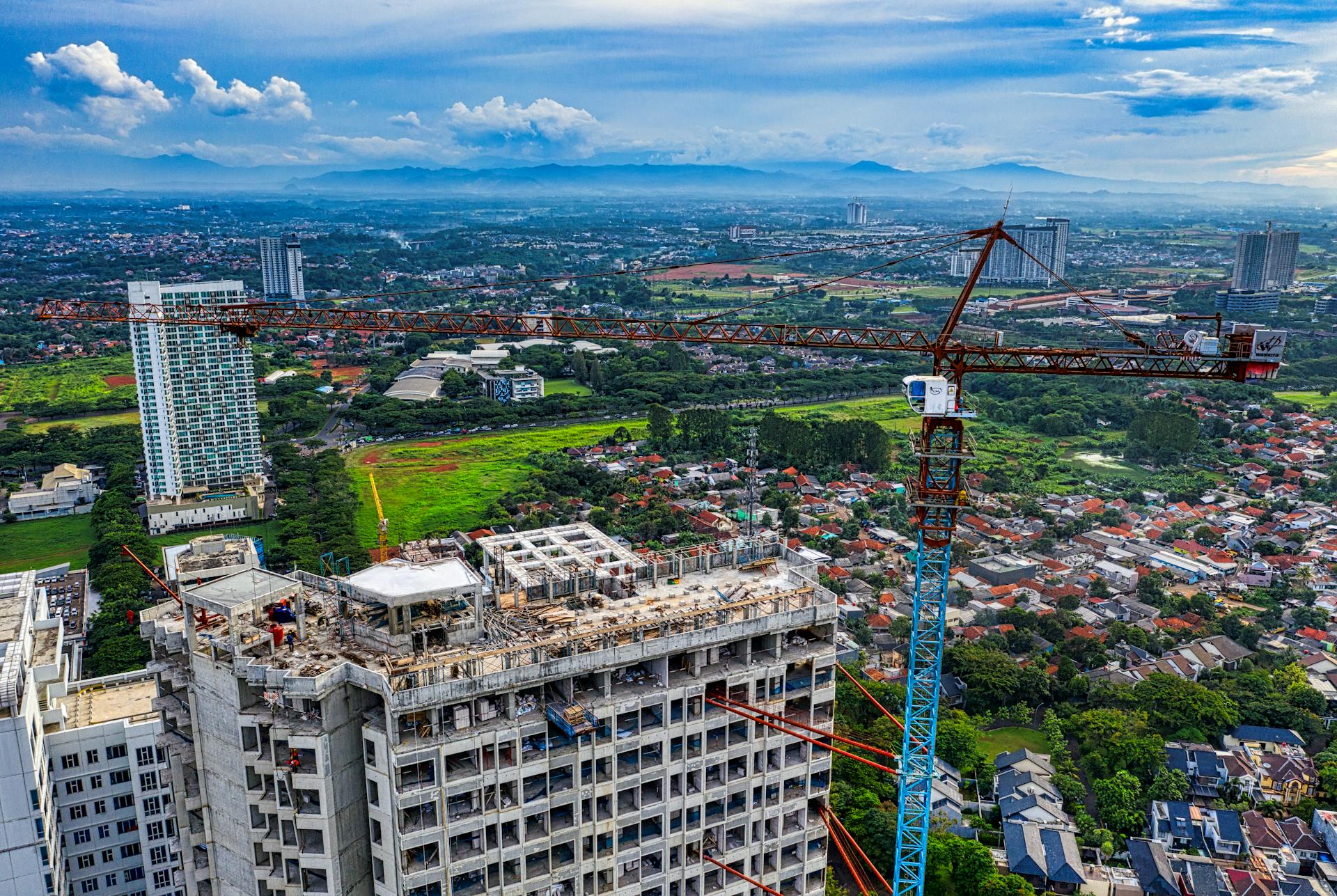 High-angle drone view of urban development with crane in Banten, Indonesia.