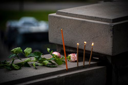 Free Burning candles and roses on a stone ledge create a somber remembrance scene. Stock Photo