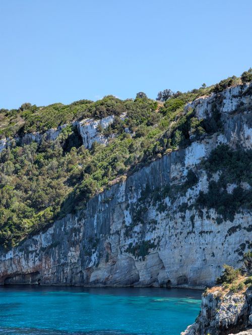 Free Breathtaking view of towering coastal cliffs with clear blue sea under a bright sky. Stock Photo