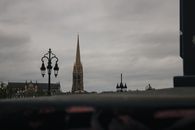 Bordeaux skyline featuring the iconic Gothic spire of Saint-Michel Basilica against a moody sky.