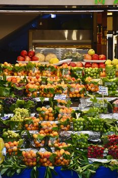 Vibrant indoor fruit market stall with assorted fresh fruits neatly arranged.