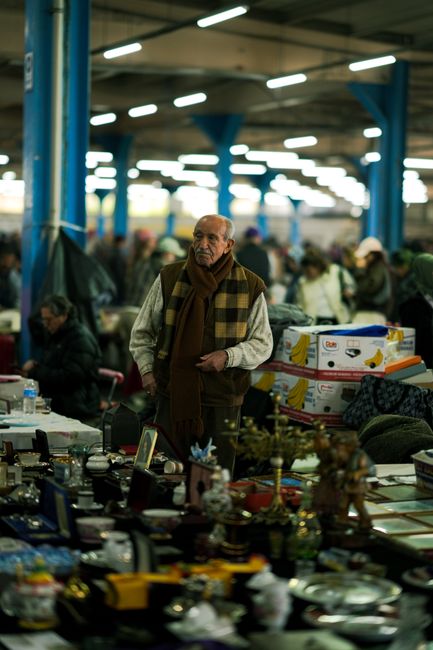 Fotomural Un anciano explorando un bullicioso mercado de pulgas cubierto en Estambul, rodeado de varios artículos a la venta.