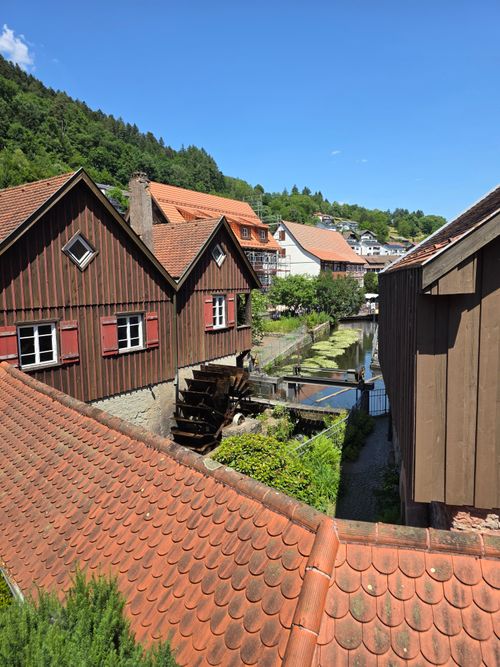 Free Charming village with traditional wooden watermill and vibrant summer landscape. Stock Photo