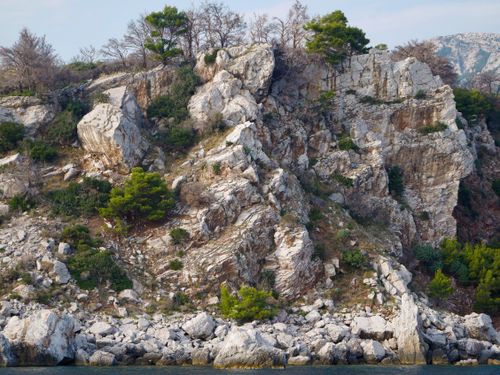 Free A rugged cliff face with sparse vegetation showing natural erosion patterns against a clear sky. Stock Photo