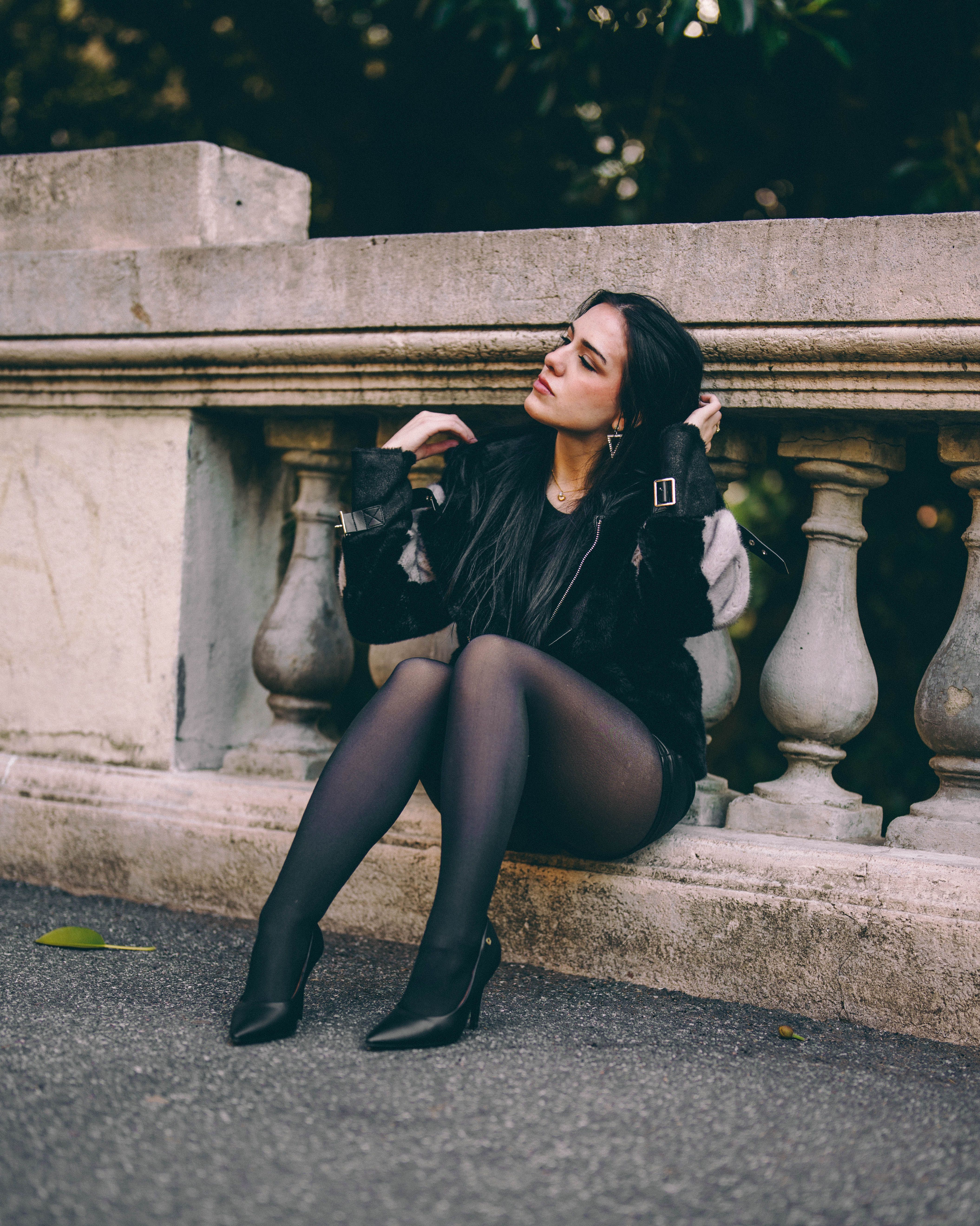 Contemplative Woman Sitting on Urban Stone Railing · Free Stock Photo