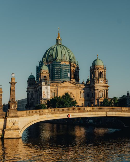 Free Stunning view of Berlin Cathedral reflecting in calm river at sunset, showcasing architectural beauty. Stock Photo