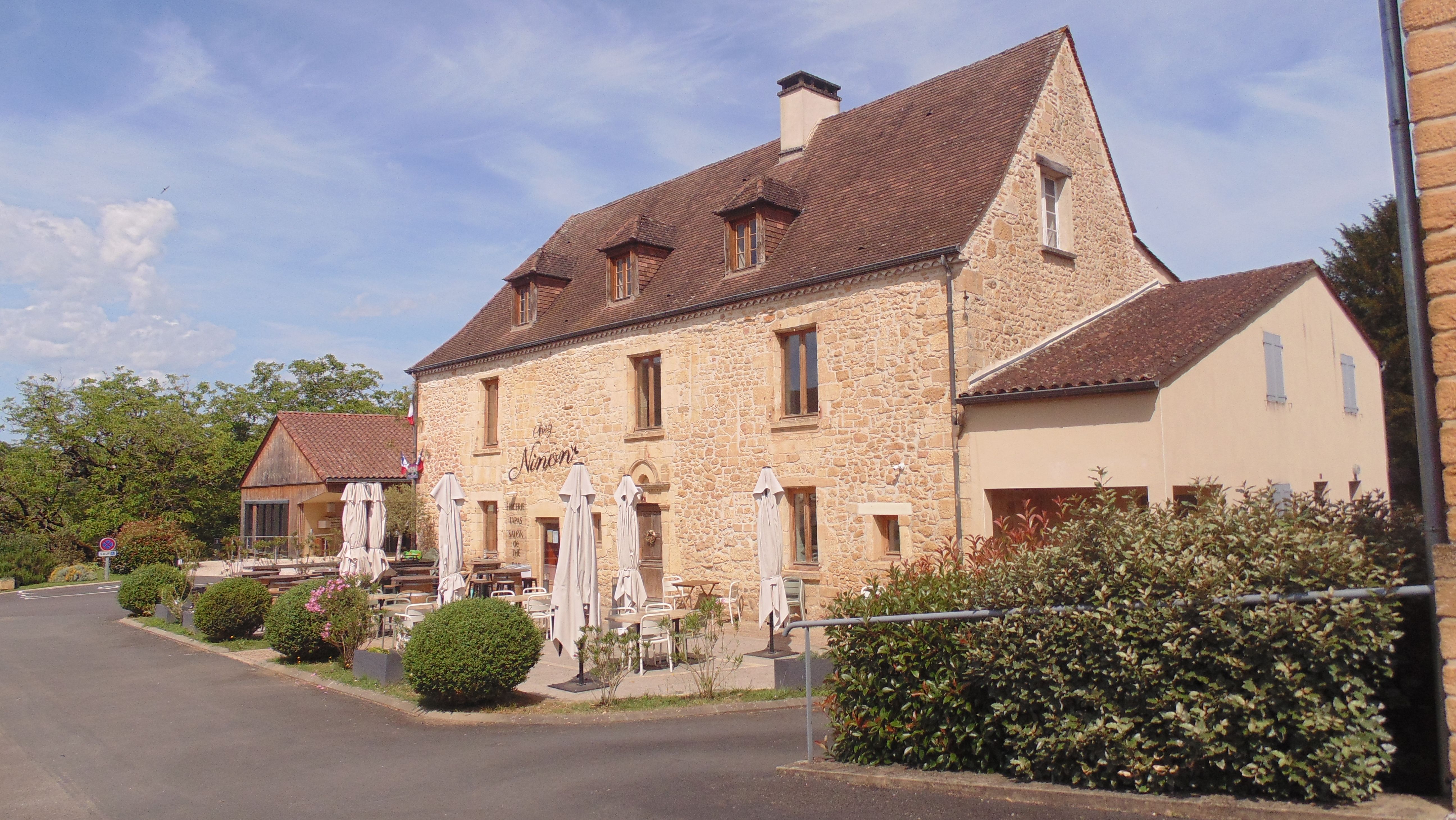 A picturesque stone building with outdoor seating in Vitrac, France.
