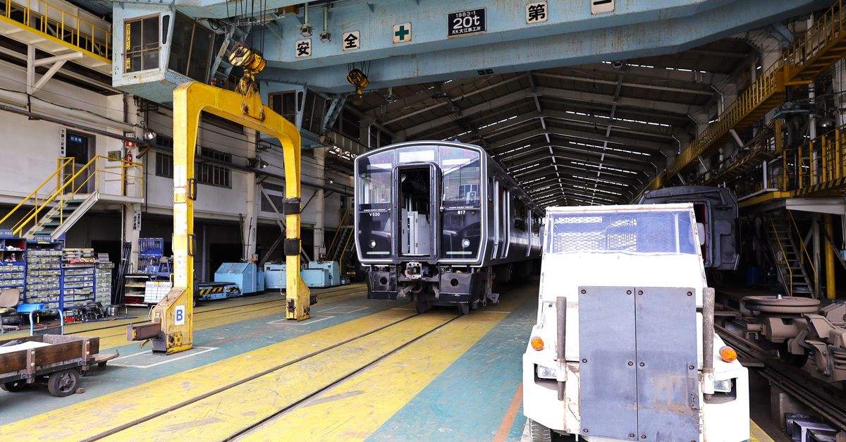 Interior view of a train maintenance facility in Kitakyushu, Japan showing trains and equipment.