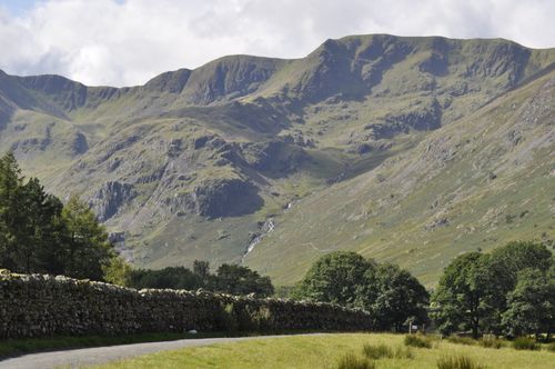 Free A breathtaking view of a mountain landscape in England, featuring rolling hills, rocky peaks, and lush greenery under a sunny sky. Stock Photo