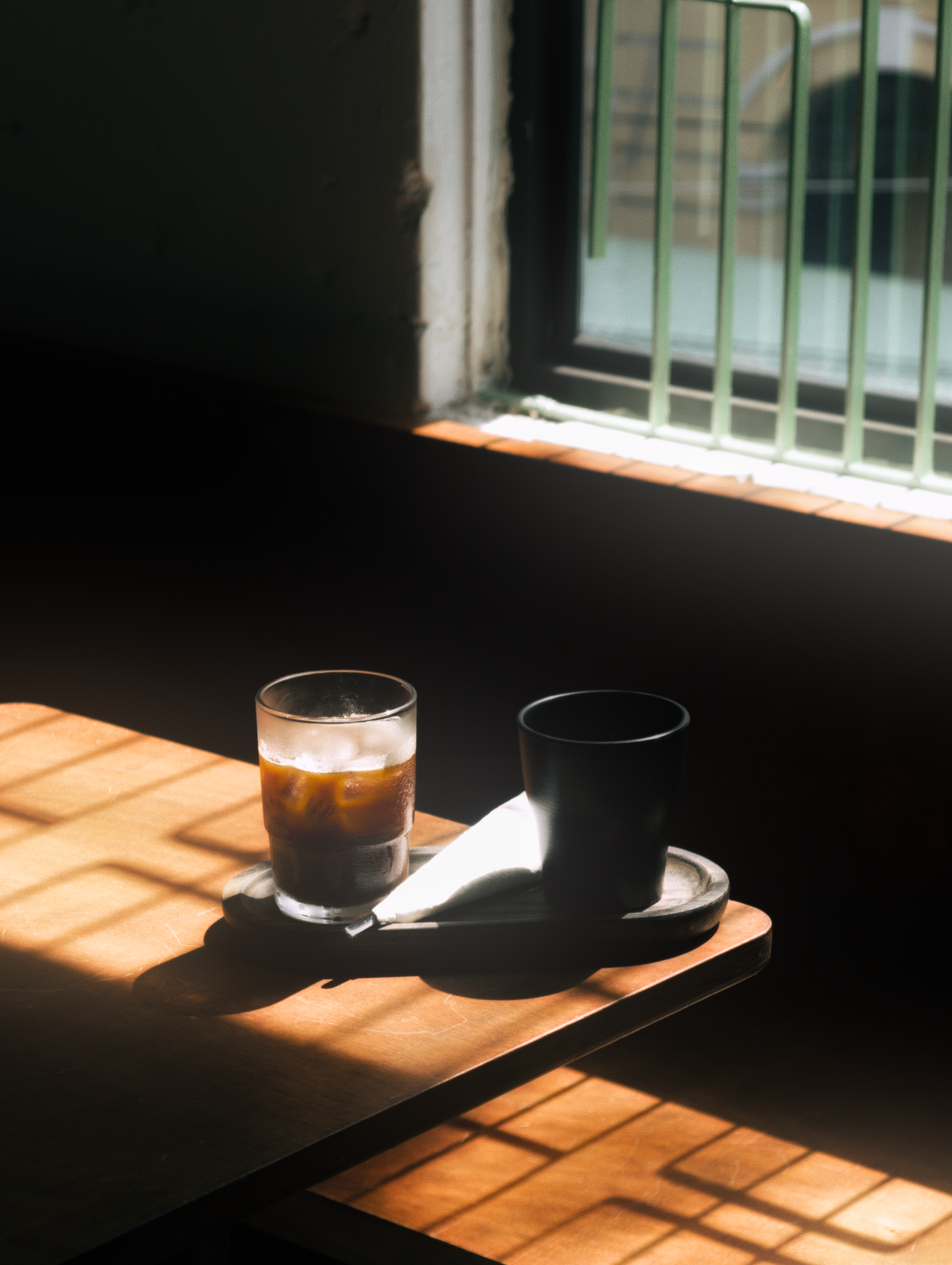 A serene coffee scene with soft light through window bars.