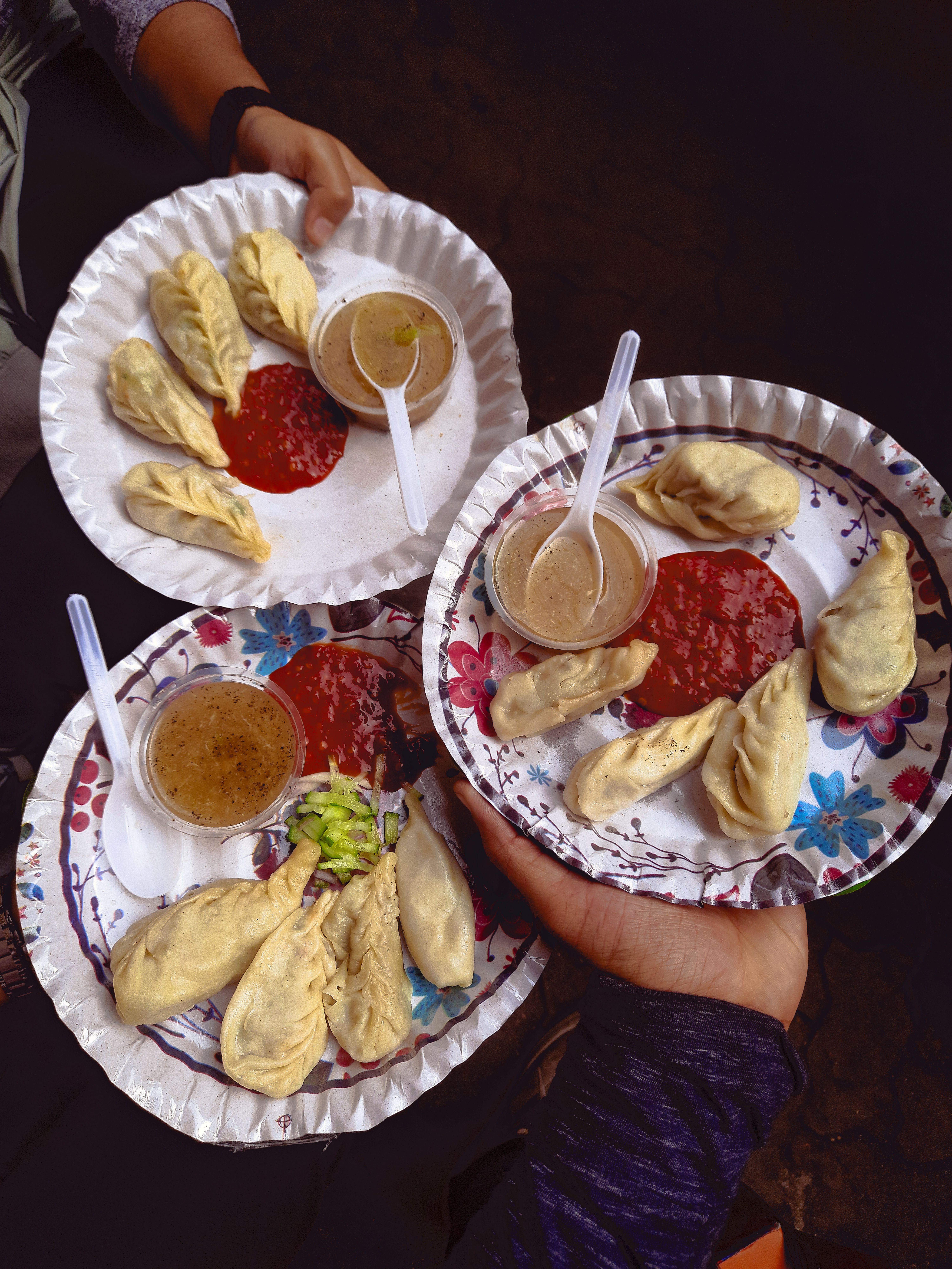 Three plates of delicious dumplings with spicy sauces, perfect representation of vibrant street food culture.