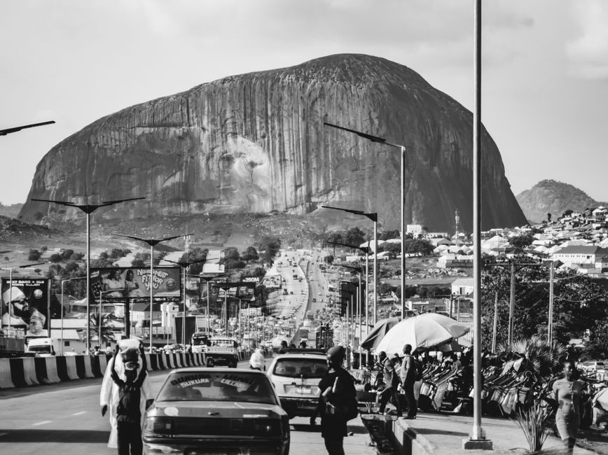 Black and white image of a busy street leading to the iconic Zuma Rock in Abuja, Nigeria.