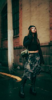Trendy young woman in chic streetwear posing confidently in an urban alleyway.