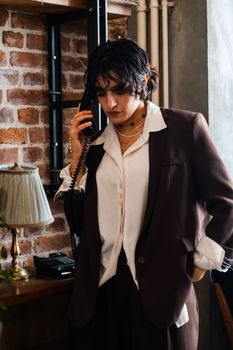 Businesswoman in a suit talking on a retro phone in a modern office setting.