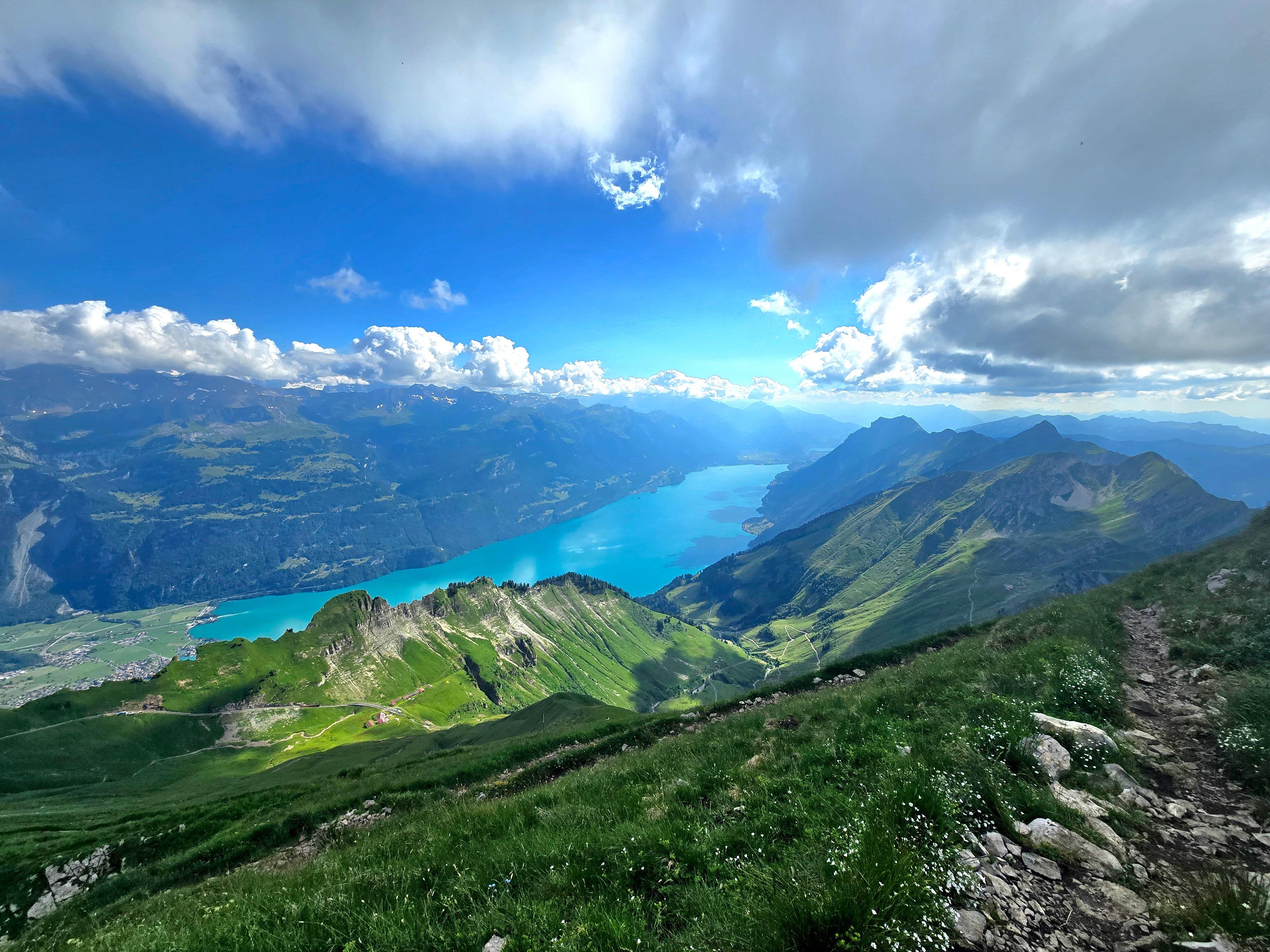 A breathtaking view of a vibrant blue lake and lush green mountains under a vast sky.
