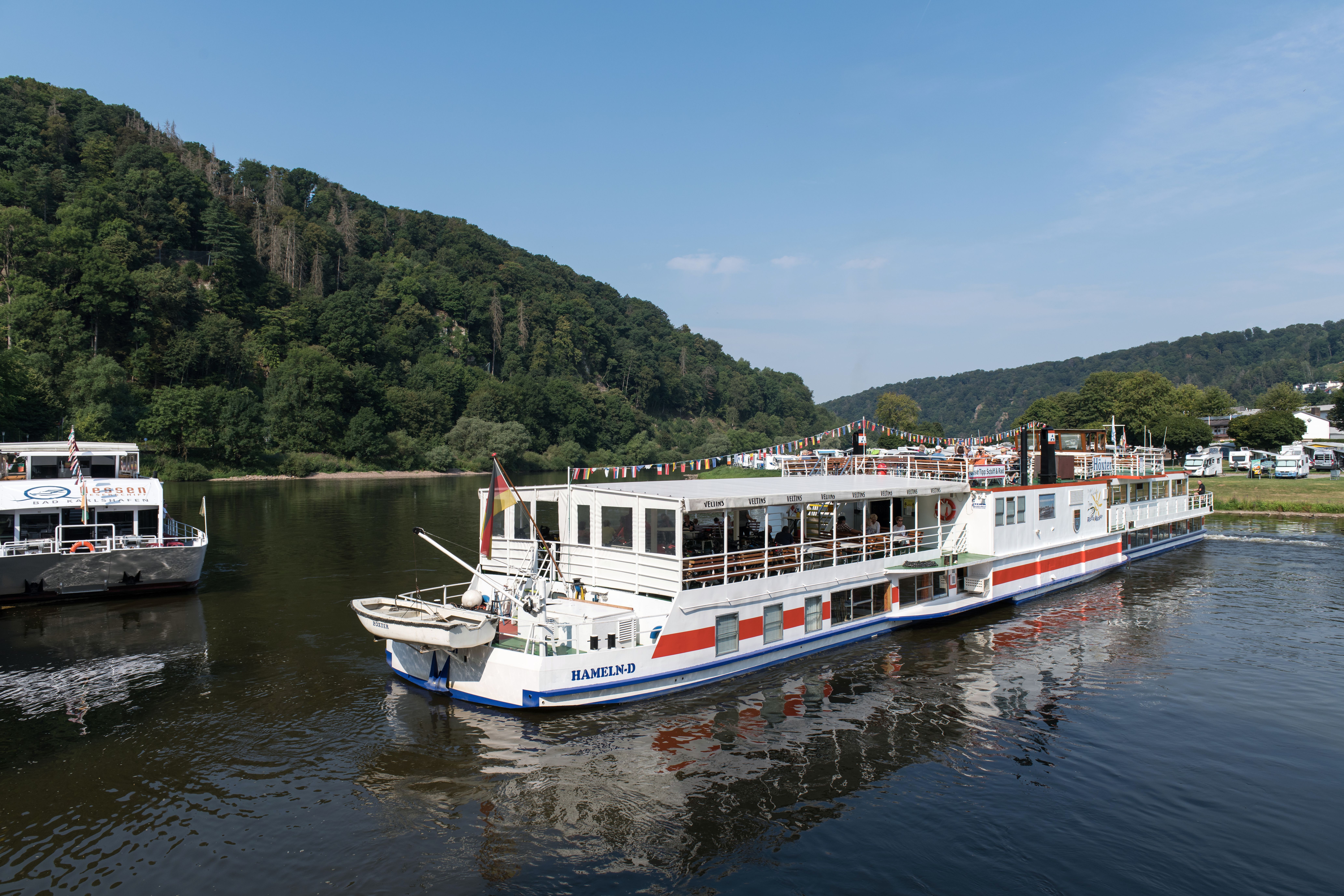 Tranquil river cruise ship navigating the scenic Weser in Bad Karlshafen, Germany.