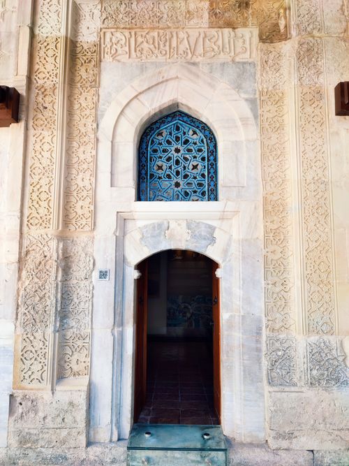 Free Detailed stone carvings and blue patterned window at a historic entrance in Sivas, Türkiye. Stock Photo