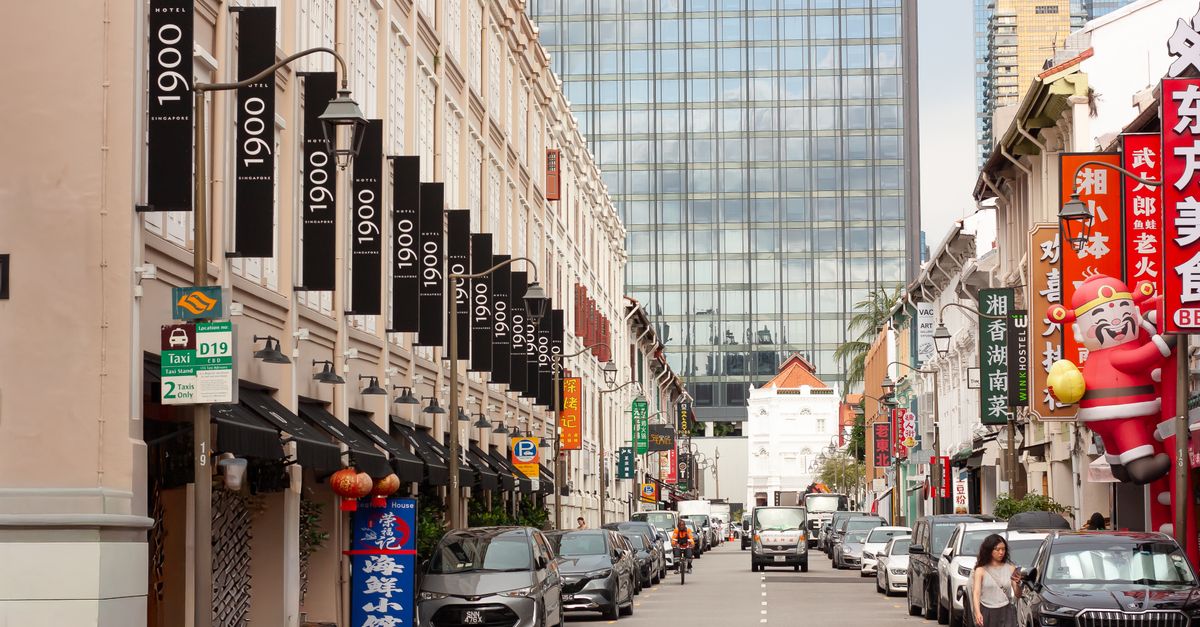 Bustling street in Chinatown, Singapore featuring traditional architecture and modern skyscrapers.