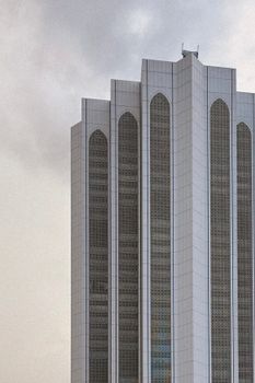 Towering modern skyscraper against a cloudy sky, showcasing urban architecture in Malaysia.