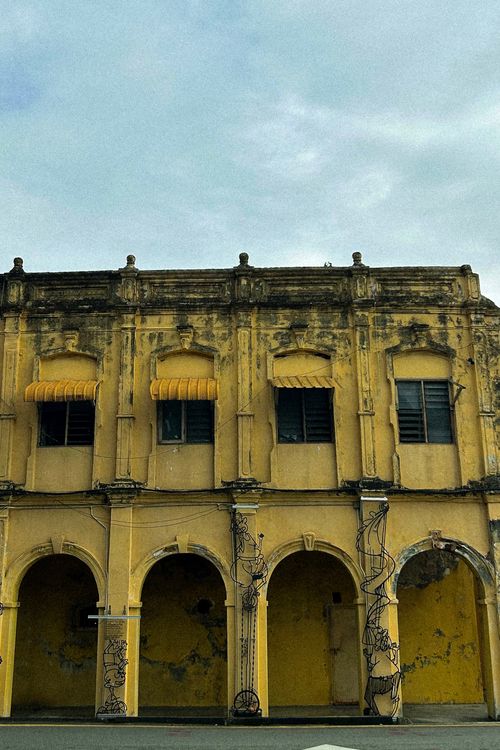 Free Aged yellow colonial building with archways and palm tree motifs in Malaysia. Stock Photo