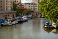 Calm scene of houseboats moored on Canal du Midi in Toulouse, France, surrounded by urban buildings.
