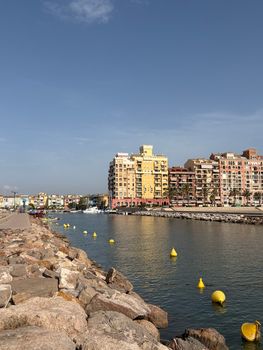 Sunny seaside view of Port Saplaya in Valencia, Spain with vibrant waterfront buildings and calm water.