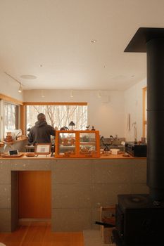 Warm café setting with a person by the window and a wood stove, creating a cozy atmosphere.