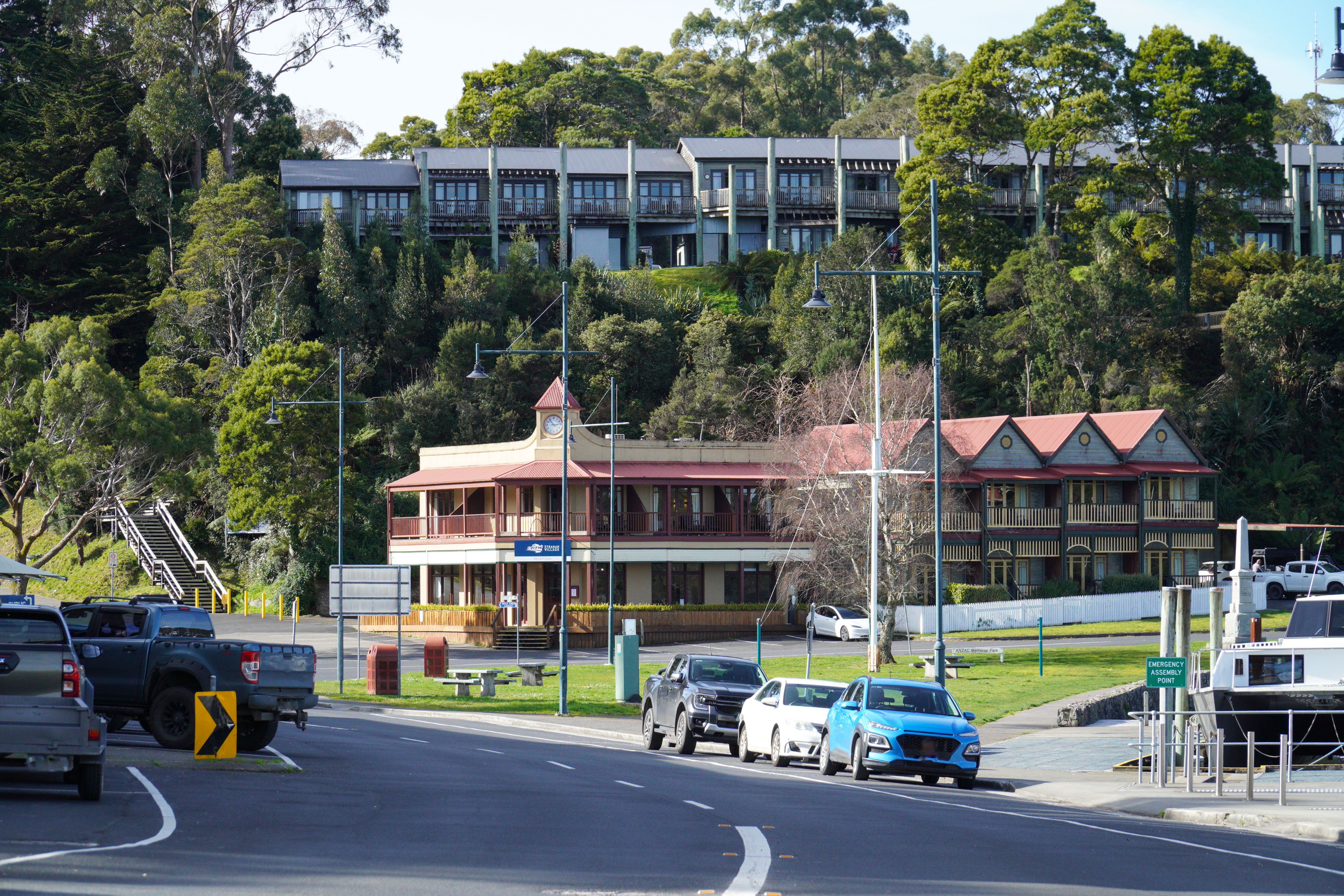 Charming street scene in Strahan, Tasmania featuring cars, classic buildings, and lush greenery