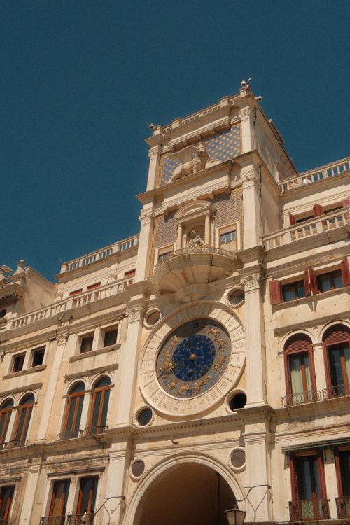 Free Renaissance-style clock tower at St. Mark's Square in Venice, Italy under a clear blue sky. Stock Photo