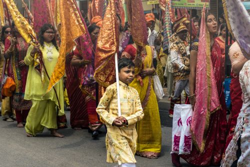 Free Colorful procession with people in traditional Indian attire holding flags on a street. Stock Photo