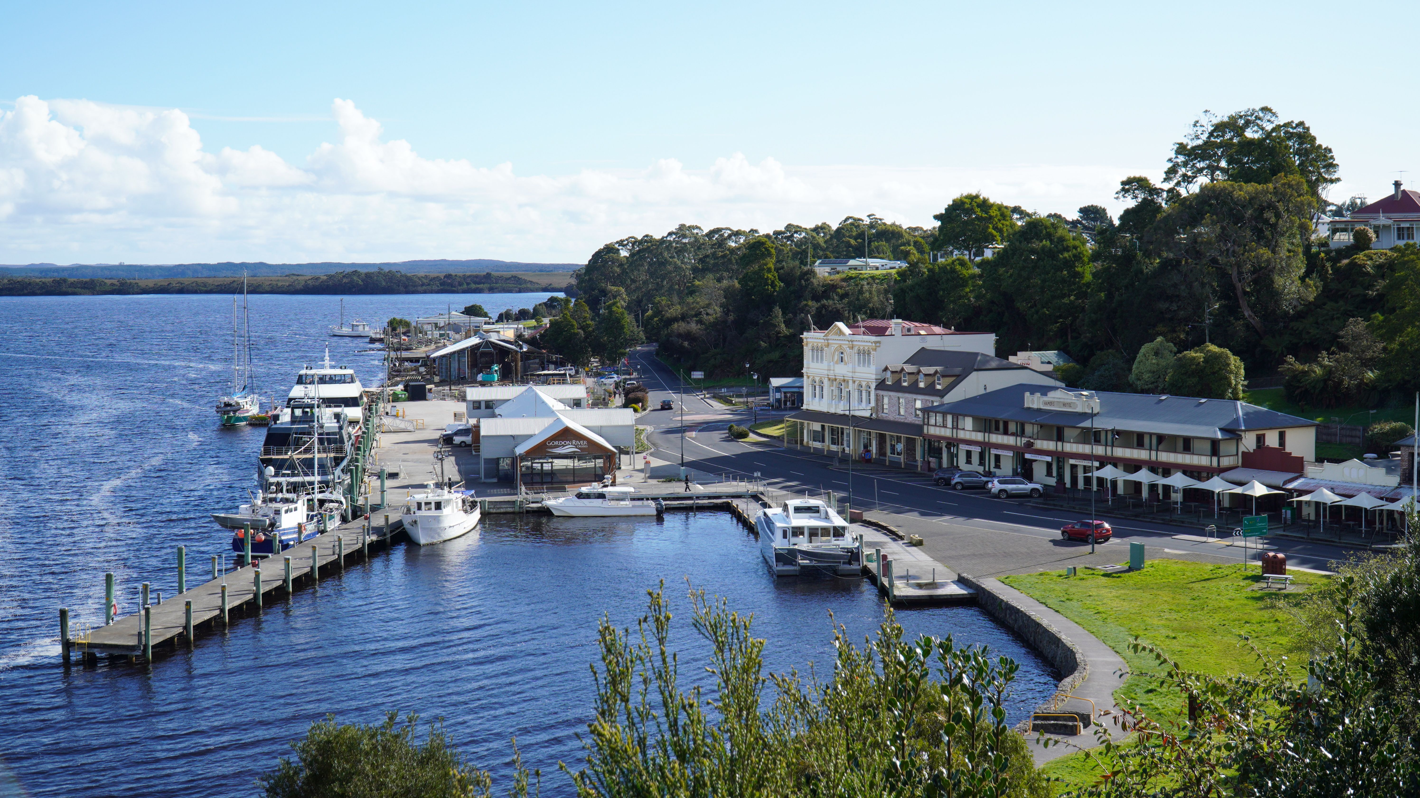 A picturesque view of Strahan Harbor in Tasmania with boats docked and historic buildings nearby.