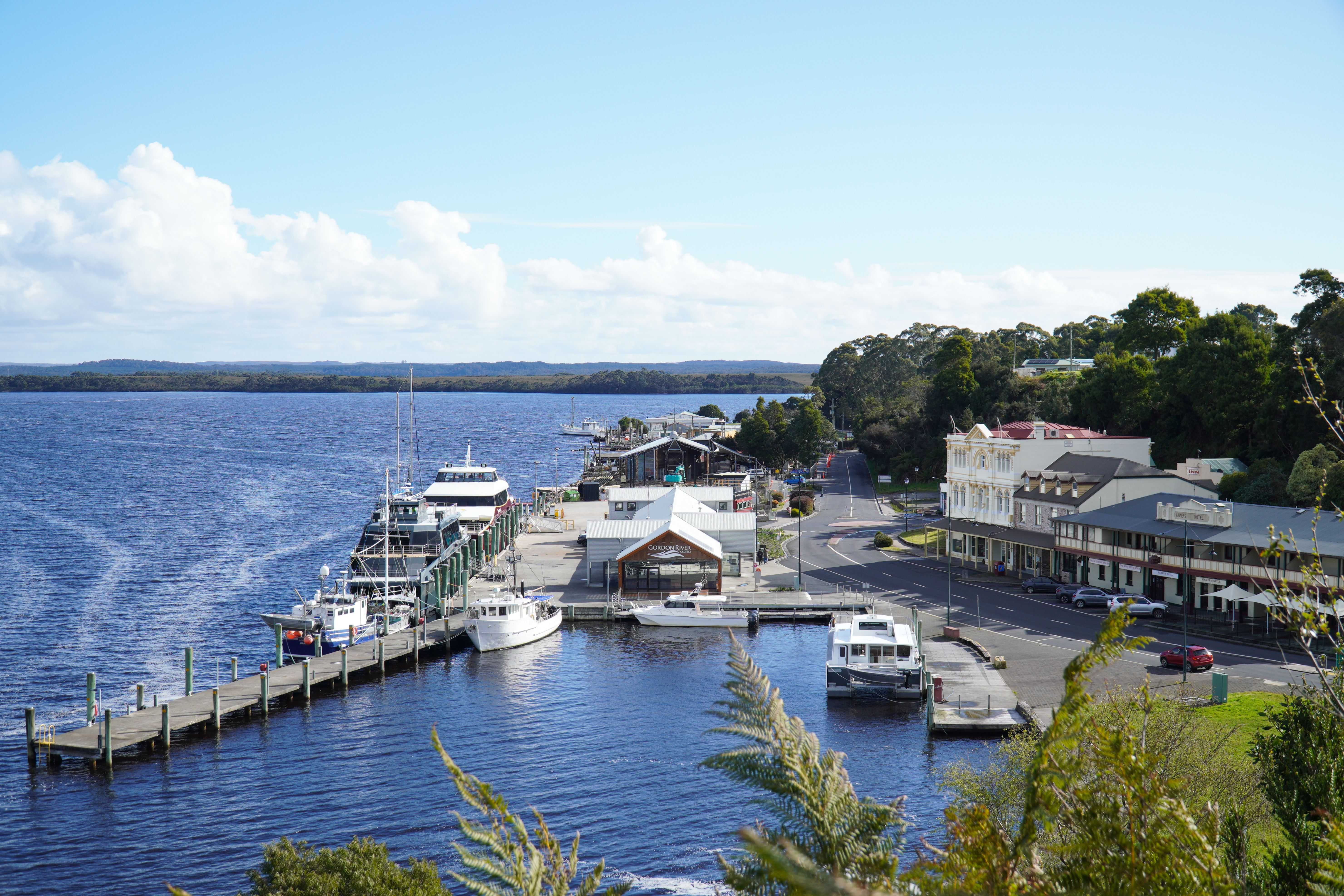 Vibrant view of Strahan's waterfront with boats docked along the pier in Tasmania.