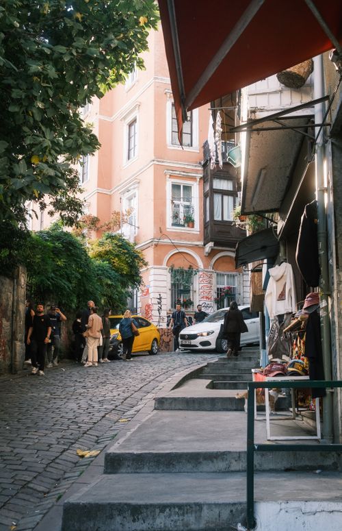 Free A vibrant street scene in a historic district with people, cars, and shops on a sunny day. Stock Photo