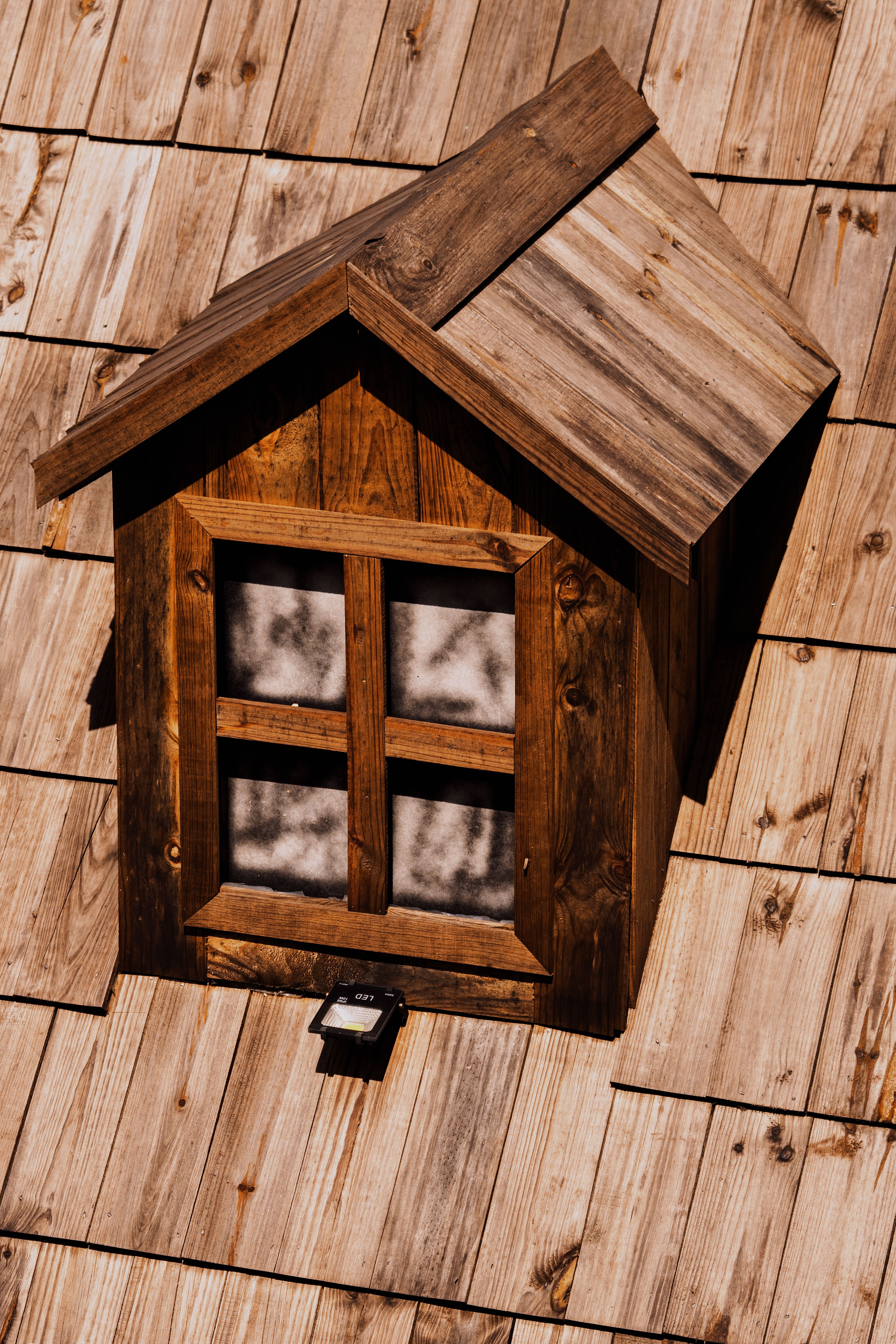 A cozy wooden attic window on a shingled roof basked in warm sunlight, showcasing rustic charm.