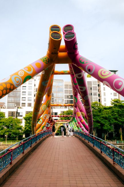 Vibrant spiral bridge in Singapore with colorful artistic designs and urban backdrop.