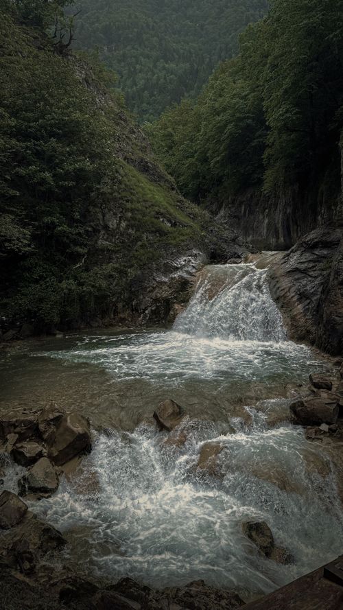 Free A tranquil waterfall cascading through a mountainous forest creates a serene nature scene. Stock Photo