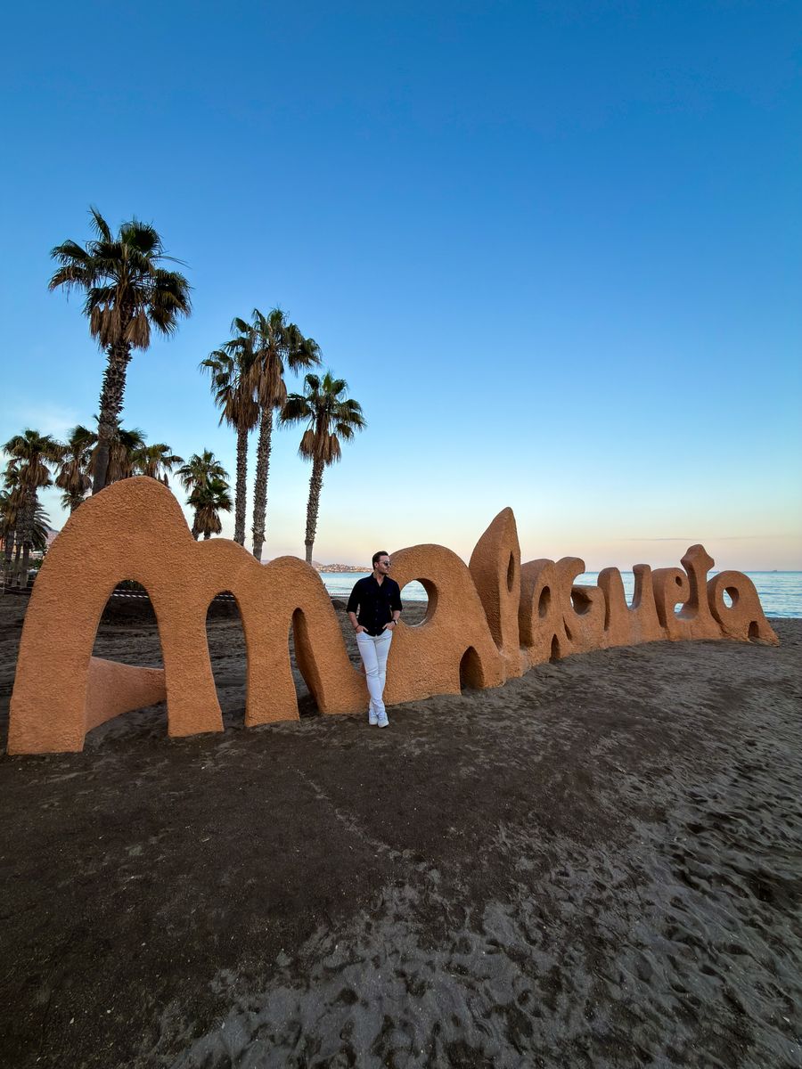 Early evening on Malagueta city beach in Malaga with palm trees and sand sculptures