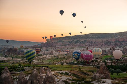 Free A breathtaking view of hot air balloons soaring over Cappadocia's unique landscape at sunrise. Stock Photo