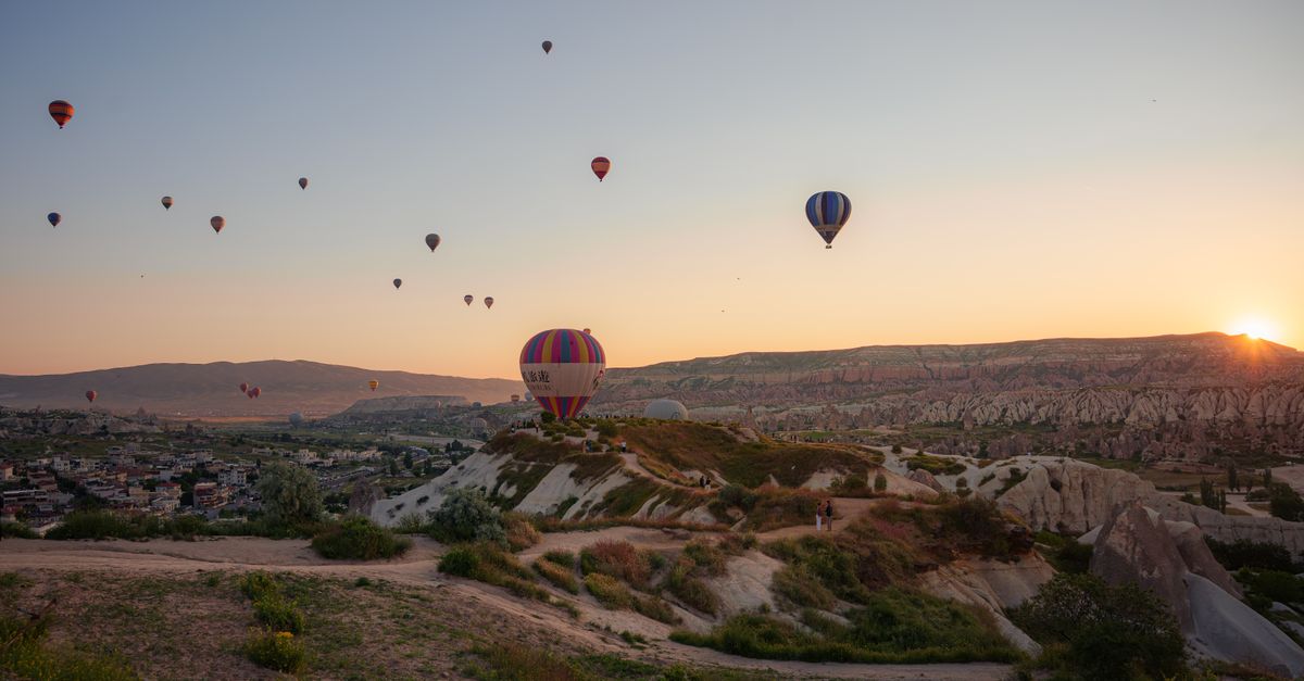 Hot air balloons rising over the rock valleys of Cappadocia at sunrise.