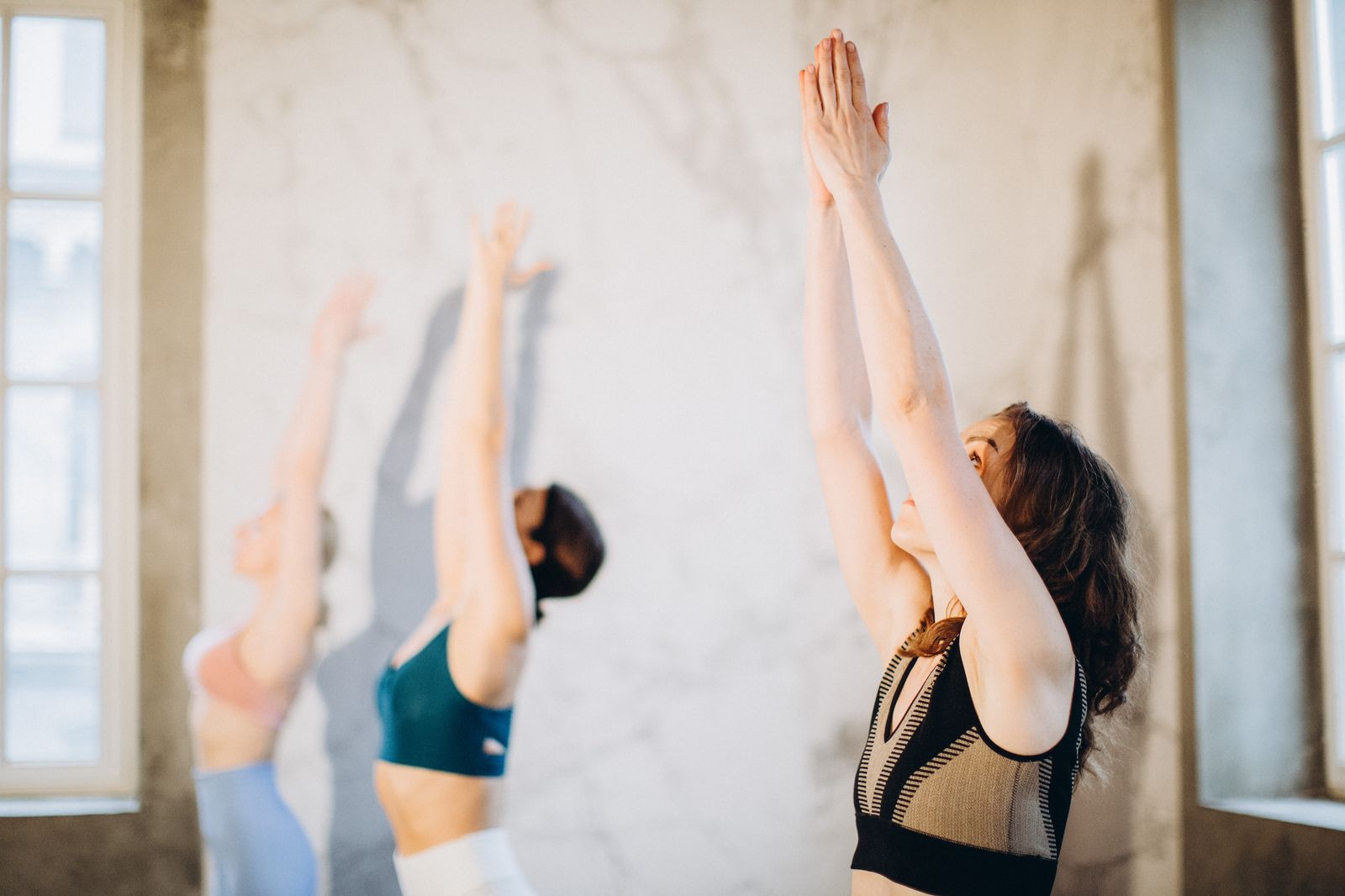 Group of women performing surya namaskar yoga poses together indoors