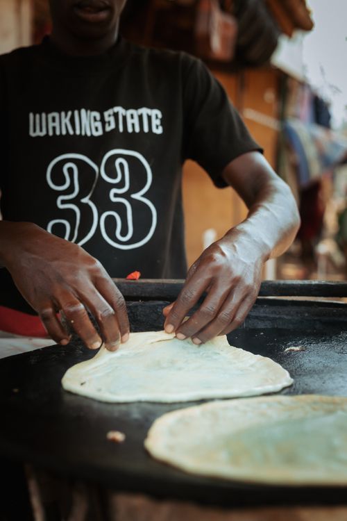 Free Street vendor crafting flatbread on an outdoor grill, focused hands visible. Stock Photo