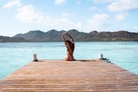 一名妇女坐在哥伦比亚加勒比海的码头上，海水和山脉碧绿