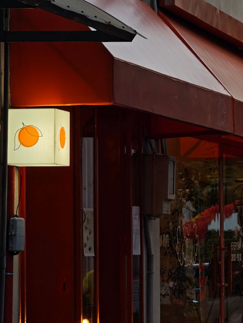 Free A cozy street cafe with a glowing orange-themed sign and warm lighting at twilight. Stock Photo