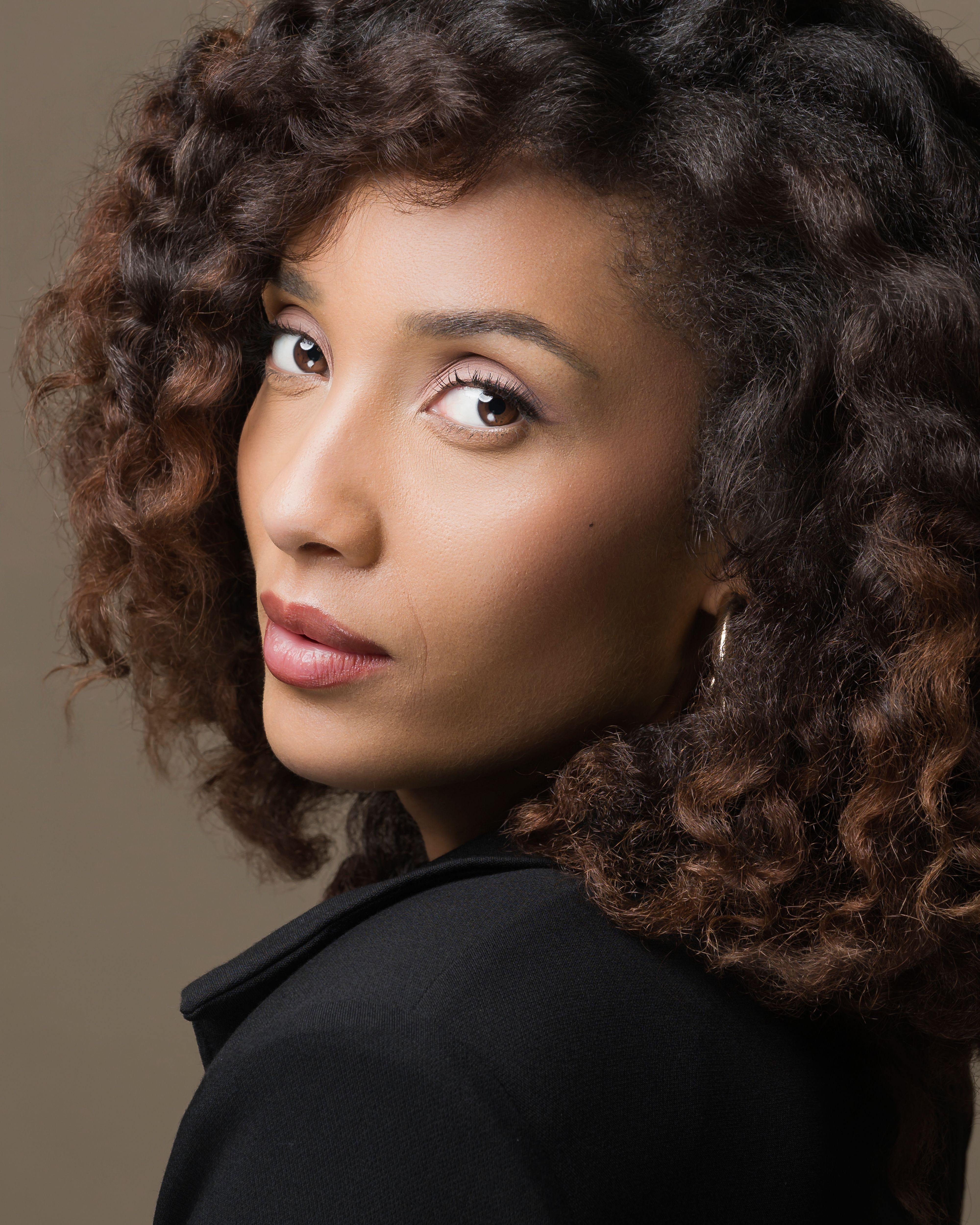 Sophisticated portrait highlighting a woman with curly hair and serene expression.
