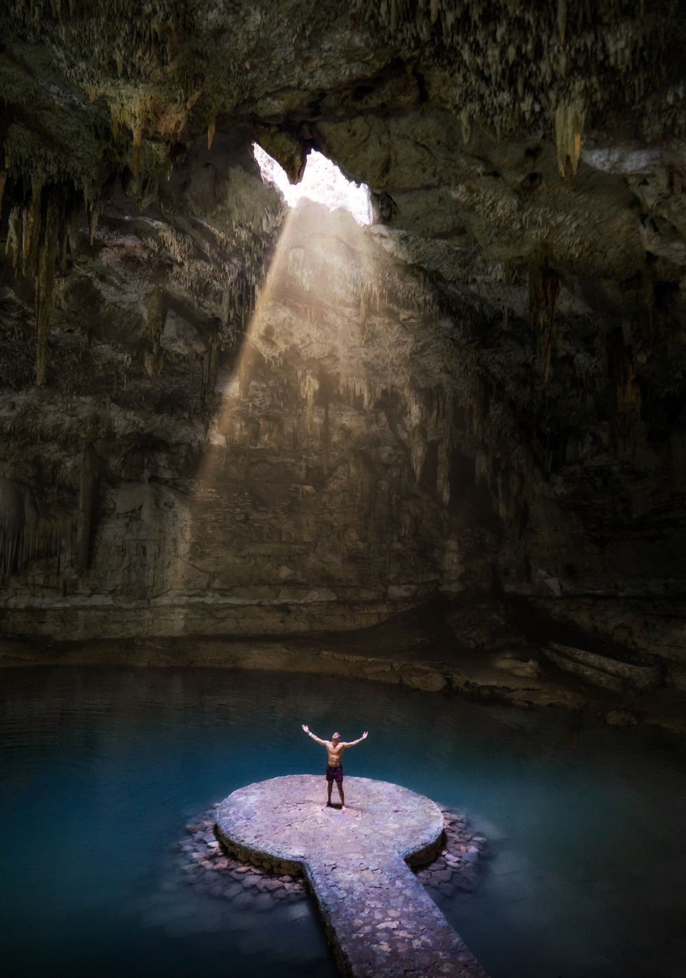Rayo de luz entrando al cenote Suytun con plataforma circular en el agua